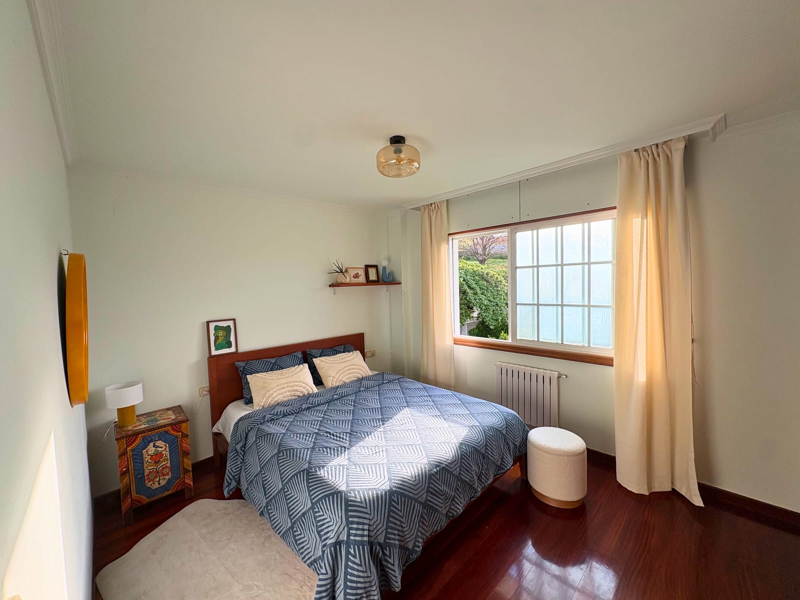 A double bedroom with retro furniture and a window onto the garden